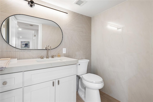 bathroom with tile walls, vanity, and toilet