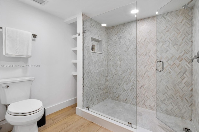 bathroom featuring wood-type flooring, toilet, and an enclosed shower