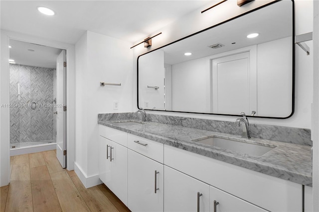 bathroom with hardwood / wood-style floors, vanity, and tiled shower