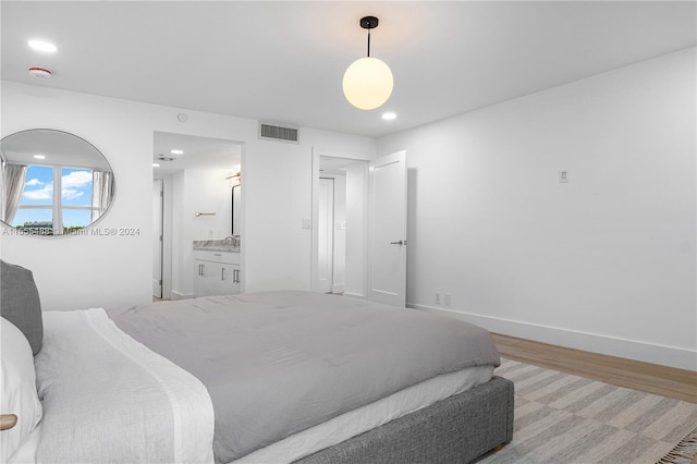 bedroom featuring connected bathroom and light hardwood / wood-style floors