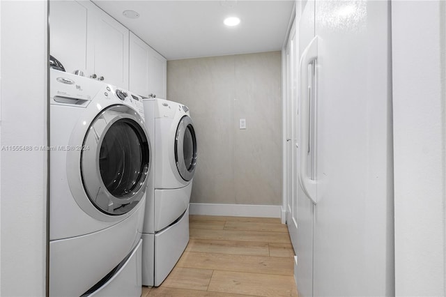 laundry room with separate washer and dryer, cabinets, and light hardwood / wood-style floors