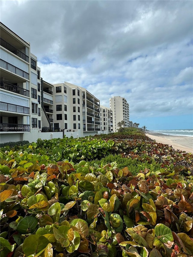 view of building exterior featuring a water view and a beach view