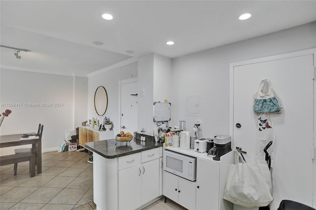 kitchen featuring light tile patterned flooring, white microwave, white cabinets, kitchen peninsula, and crown molding