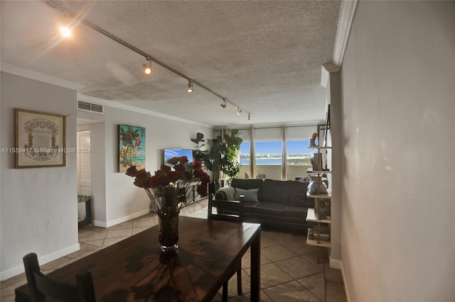 tiled dining area with ornamental molding, rail lighting, a textured ceiling, and a water view