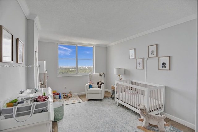 bedroom featuring ornamental molding, a nursery area, and a textured ceiling