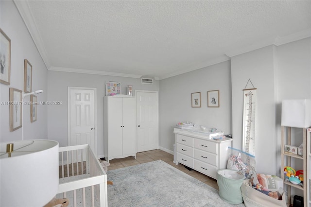 tiled bedroom with a crib, ornamental molding, and a textured ceiling