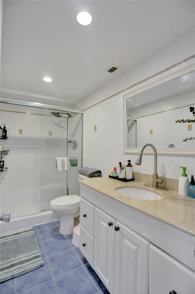 bathroom with tile patterned flooring, vanity, a shower with door, and toilet