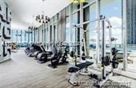 gym featuring floor to ceiling windows, an inviting chandelier, and wood-type flooring