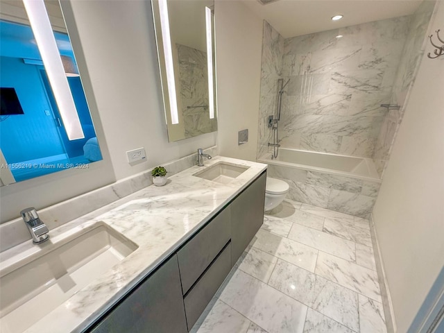 full bathroom featuring tile flooring, toilet, tiled shower / bath, and double sink vanity