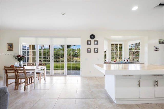 kitchen featuring white cabinets, a wealth of natural light, and light tile flooring