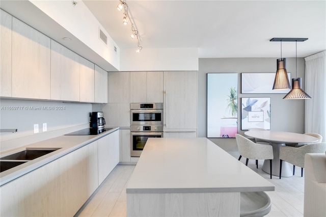 kitchen with pendant lighting, stainless steel double oven, rail lighting, black electric stovetop, and a center island