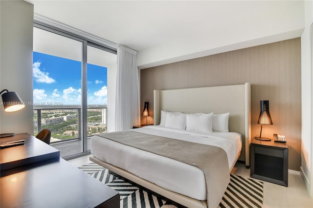 bedroom featuring floor to ceiling windows, light hardwood / wood-style floors, and access to outside