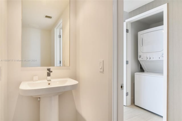 bathroom featuring stacked washer and dryer and tile flooring