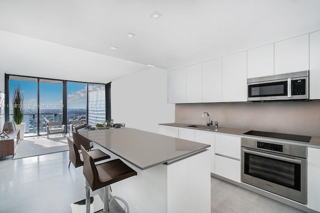 kitchen with backsplash, sink, a kitchen island, white cabinetry, and stainless steel appliances