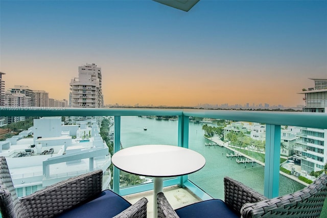 balcony at dusk featuring a water view