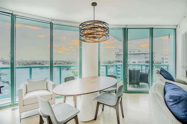 dining space with a water view, light hardwood / wood-style flooring, floor to ceiling windows, and a healthy amount of sunlight