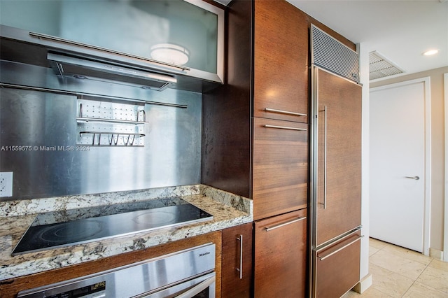 kitchen featuring light stone countertops, black electric stovetop, paneled refrigerator, oven, and light tile patterned flooring