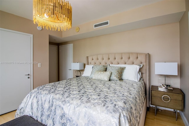 bedroom featuring light hardwood / wood-style flooring and a chandelier