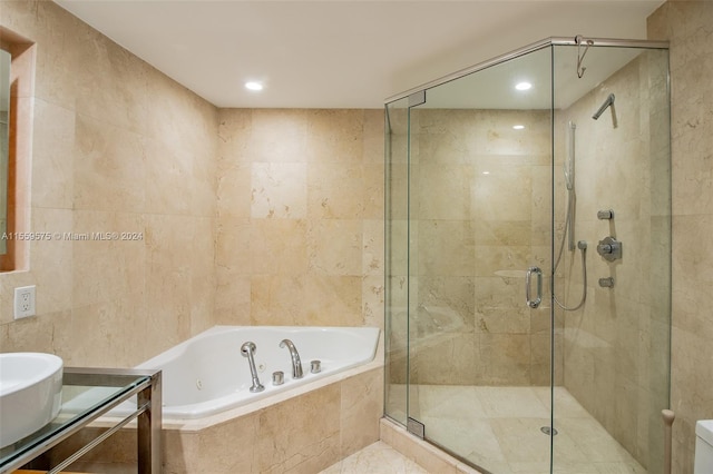 bathroom with shower with separate bathtub and tile walls