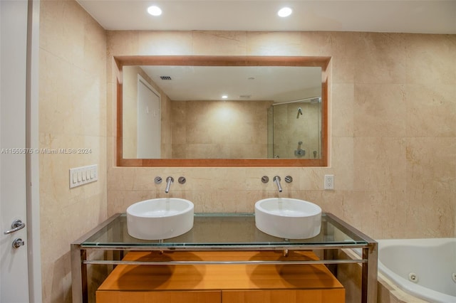 bathroom featuring a washtub, vanity, and tile walls