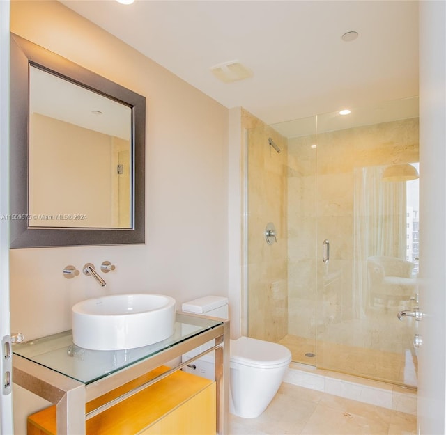 bathroom with an enclosed shower, vanity, toilet, and tile patterned flooring