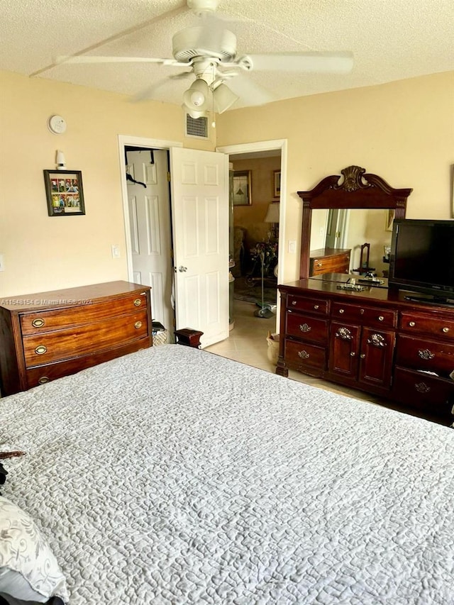 tiled bedroom with ceiling fan and a textured ceiling