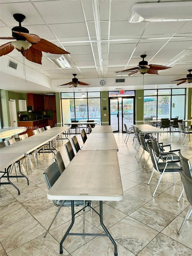 dining area with ceiling fan, light tile floors, and a paneled ceiling