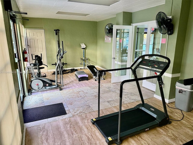 workout area with light hardwood / wood-style flooring and french doors