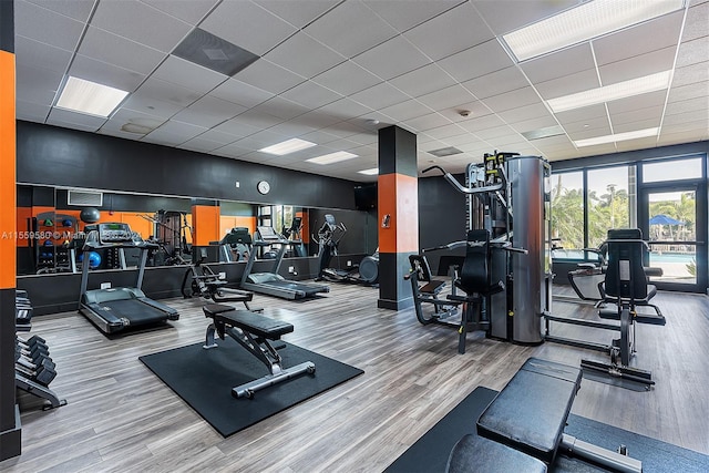 workout area with light wood-type flooring and a paneled ceiling