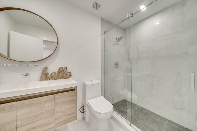 bathroom with a shower with shower door, tile flooring, vanity, and toilet