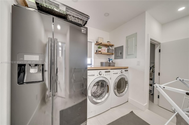 clothes washing area with washing machine and clothes dryer and light tile floors