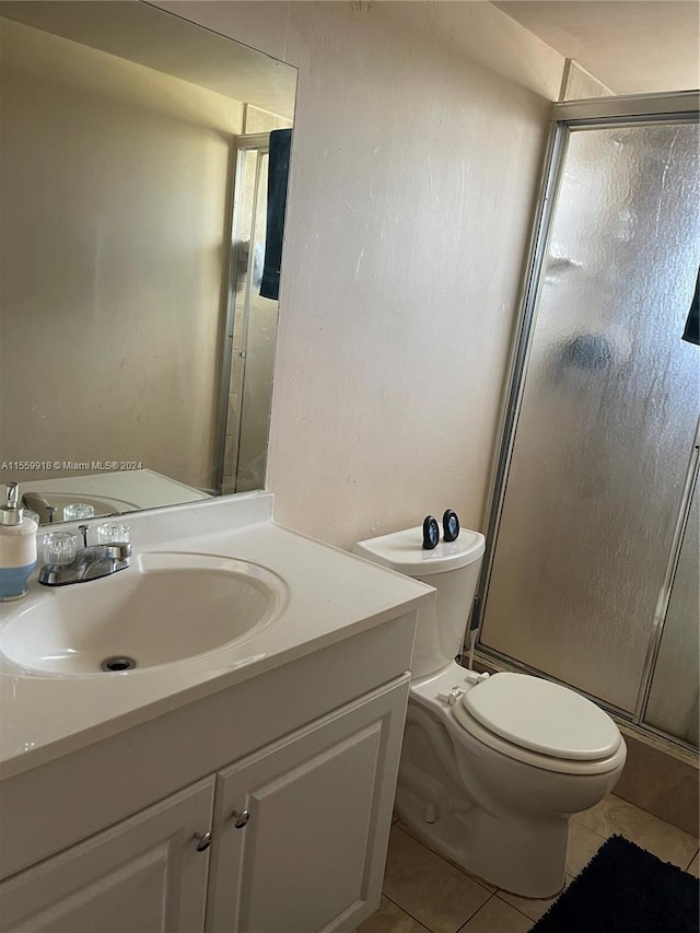 bathroom featuring toilet, a shower with door, tile floors, and vanity with extensive cabinet space