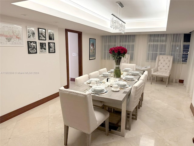 tiled dining room with a raised ceiling and a chandelier