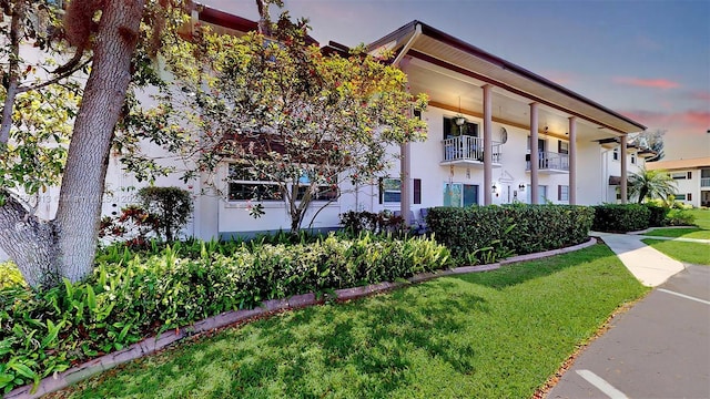 view of front facade featuring a balcony and a lawn