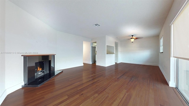 unfurnished living room with dark hardwood / wood-style flooring and a textured ceiling