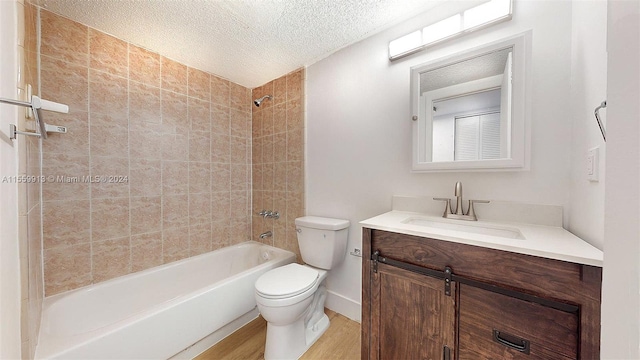 full bathroom with wood-type flooring, a textured ceiling, toilet, vanity, and tiled shower / bath