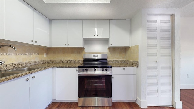 kitchen with dark wood-type flooring, backsplash, white cabinetry, and stainless steel electric range oven