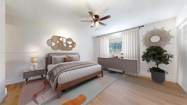 bedroom featuring a closet, a textured ceiling, ceiling fan, and light wood-type flooring