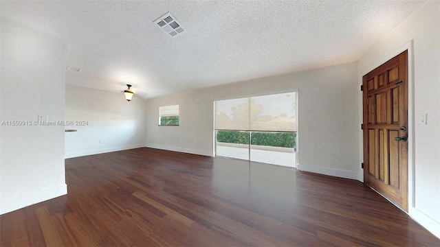 spare room with a textured ceiling, vaulted ceiling, and dark hardwood / wood-style flooring