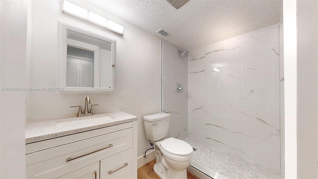 bathroom featuring wood-type flooring, a textured ceiling, toilet, vanity, and a tile shower