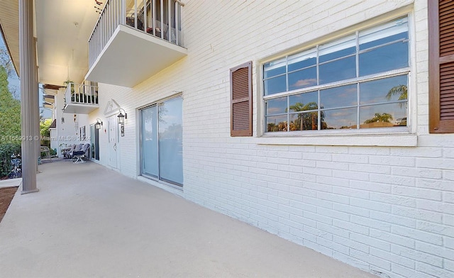 view of exterior entry featuring a balcony and a patio area