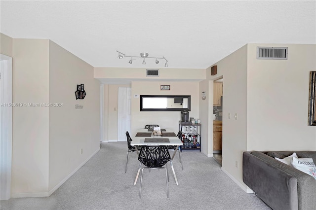 carpeted dining area featuring track lighting