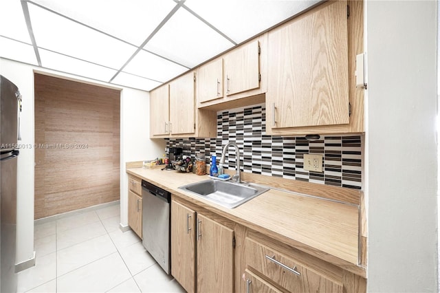 kitchen with light brown cabinetry, sink, light tile floors, stainless steel dishwasher, and tasteful backsplash