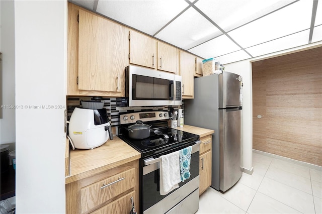 kitchen with light brown cabinets, a drop ceiling, light tile flooring, tasteful backsplash, and stainless steel appliances