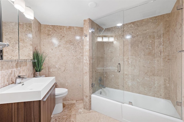 full bathroom with tile walls, combined bath / shower with glass door, vanity, and toilet