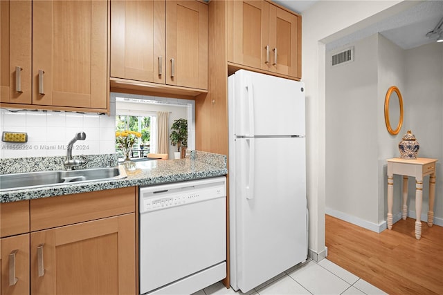 kitchen with sink, white appliances, light tile patterned floors, tasteful backsplash, and light stone countertops