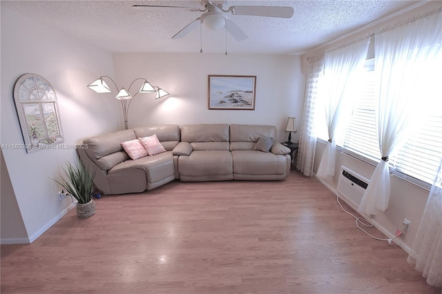 unfurnished living room with ceiling fan, light hardwood / wood-style floors, a textured ceiling, and a wall mounted AC