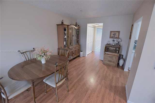 dining room with light wood-type flooring and a textured ceiling