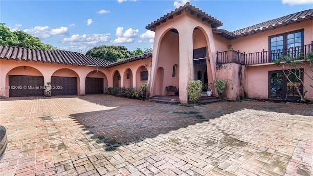 mediterranean / spanish house with a tiled roof, decorative driveway, an attached garage, and stucco siding