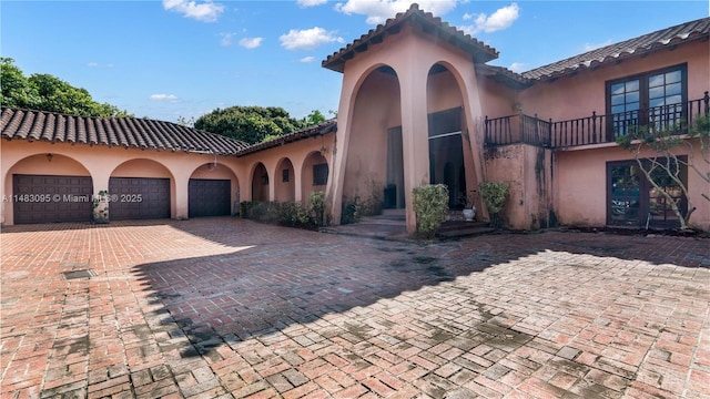 mediterranean / spanish home featuring an attached garage, decorative driveway, and stucco siding